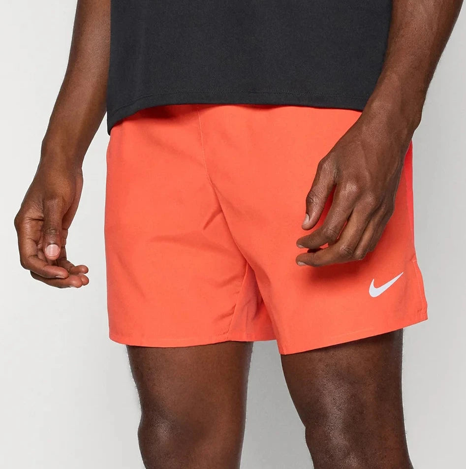 Person wearing bright orange Nike shorts on a white background