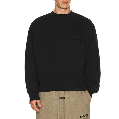 Person wearing a black sweatshirt and beige pants on a white background
