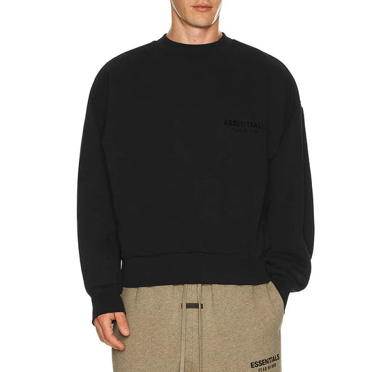 Person wearing a black sweatshirt and beige pants on a white background