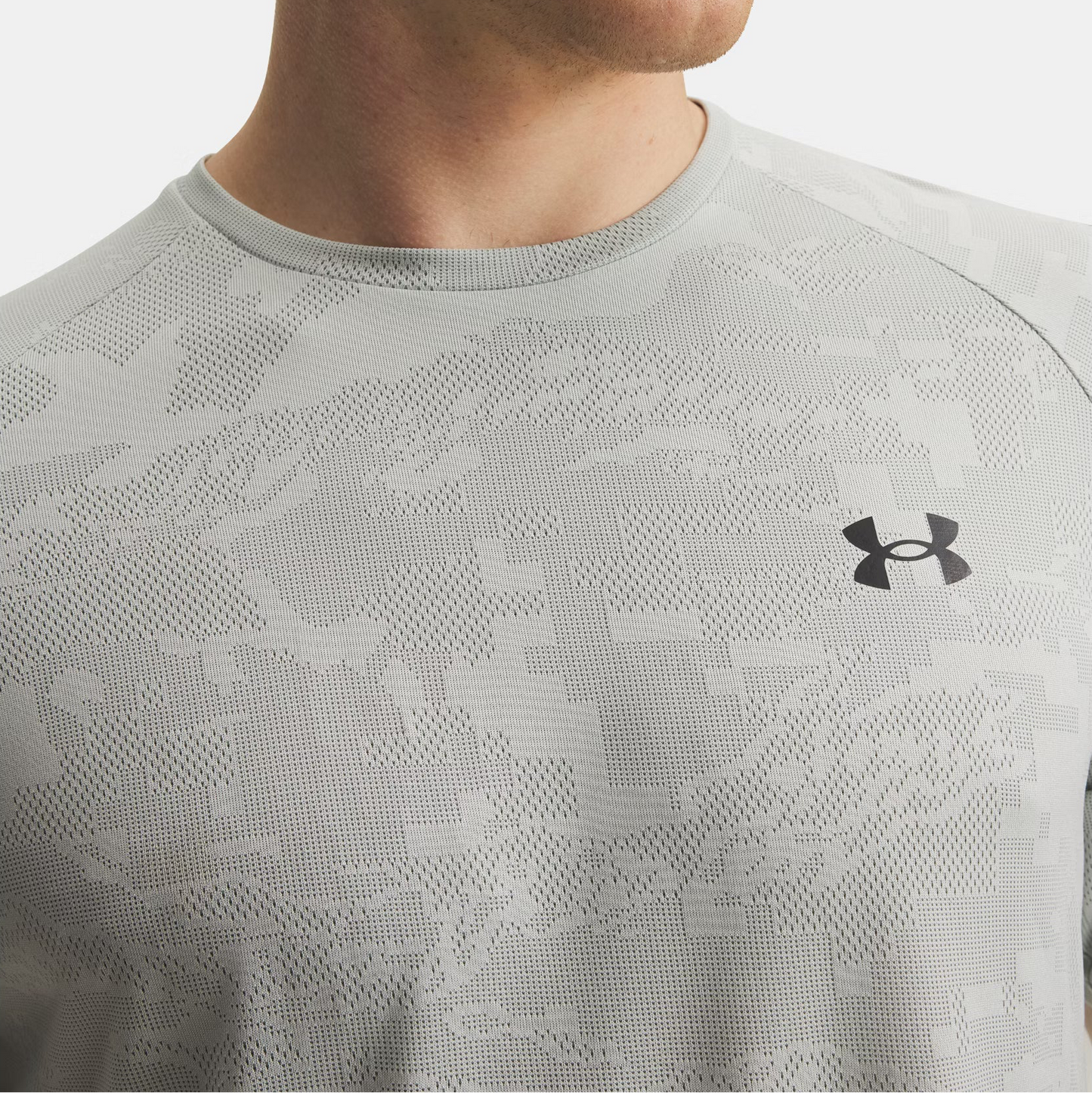 Close-up of a person wearing a gray patterned Under Armour shirt.