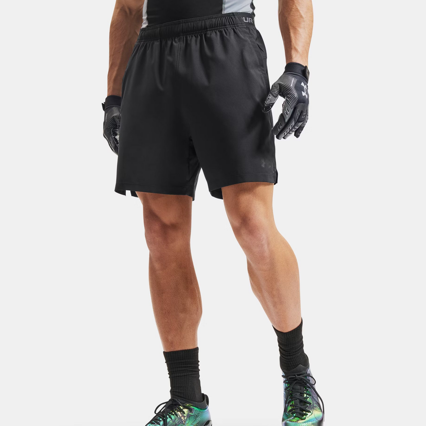 Person wearing black athletic shorts, gloves, and cleats on a white background