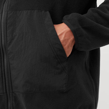 Close-up of a black jacket with a pocket showing pink lining on a light gray background