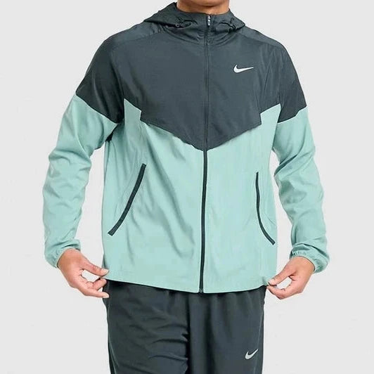 Person wearing a two-tone jacket and pants with Nike logo on a light gray background