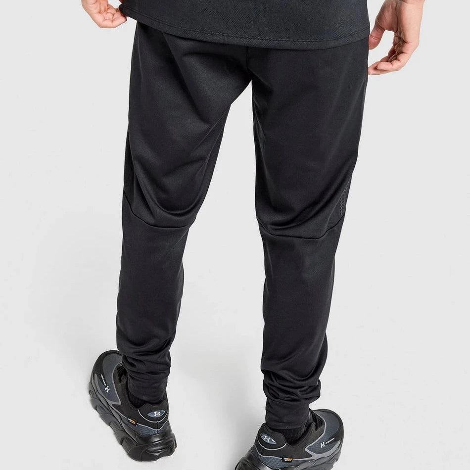 Person wearing black jogger pants and black shoes on a light gray background